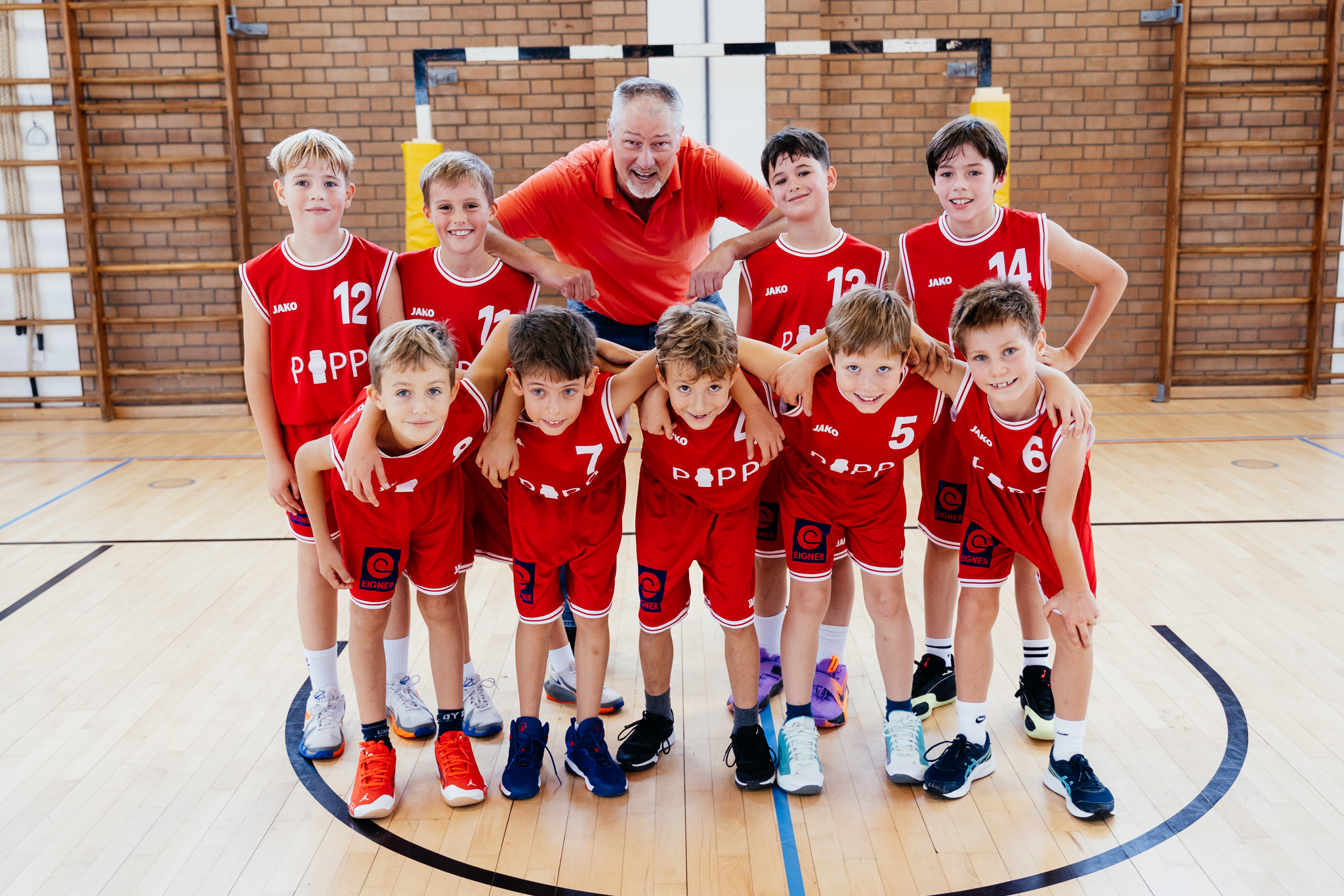 Die U10-1 des TSV Nördlingen in roten Trikots mit ihrem Trainer in der Halle